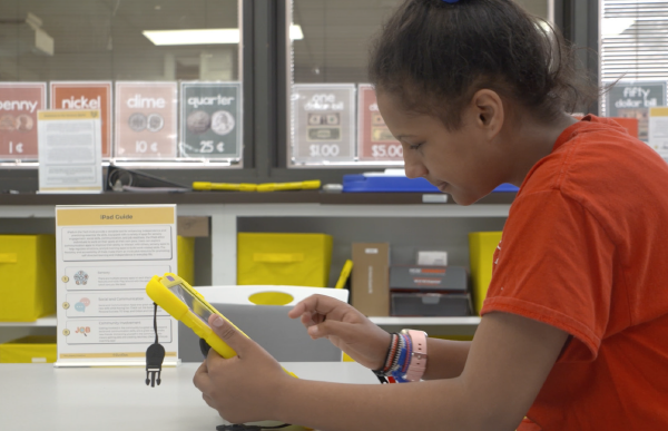 Profile of girl wearing an orange shirt using a tablet device