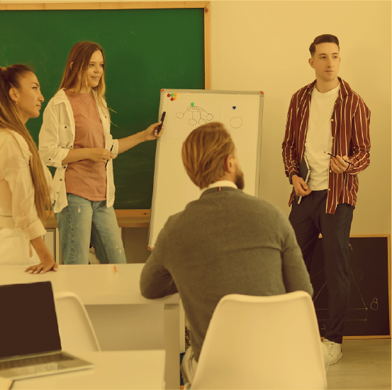 Teen stands in front of a whiteboard presenting to peers and older adult.