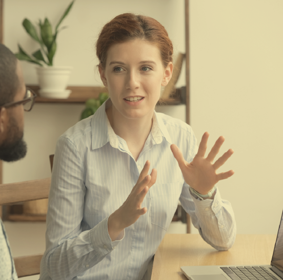 Young woman in professional attire expressing excitement during a discussion with another professional.