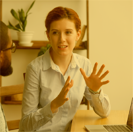 Young woman in professional attire expressing excitement during a discussion with another professional.
