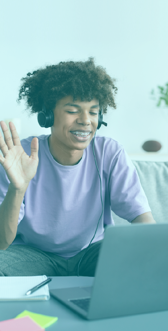 Young teen boy waving while on a call on his laptop